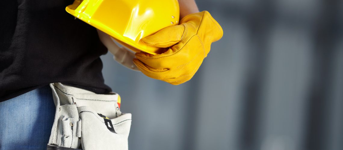 builder with yellow helmet and working gloves on building site