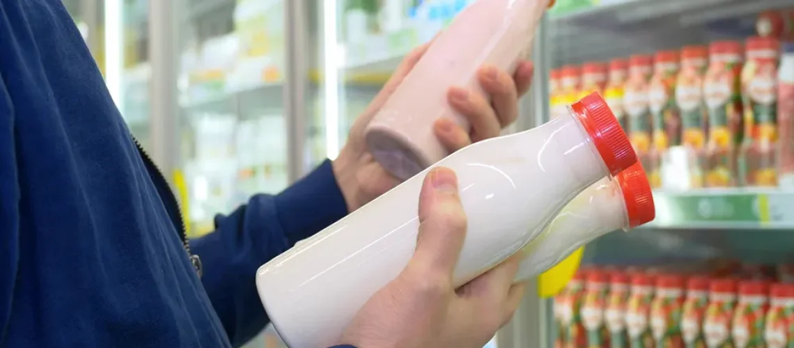 Homem segurando duas garrafas de leite - a importância da refrigeração